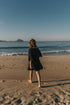 person-in-a-black-dress-walks-on-the-beach - Fiesta Resortwear 